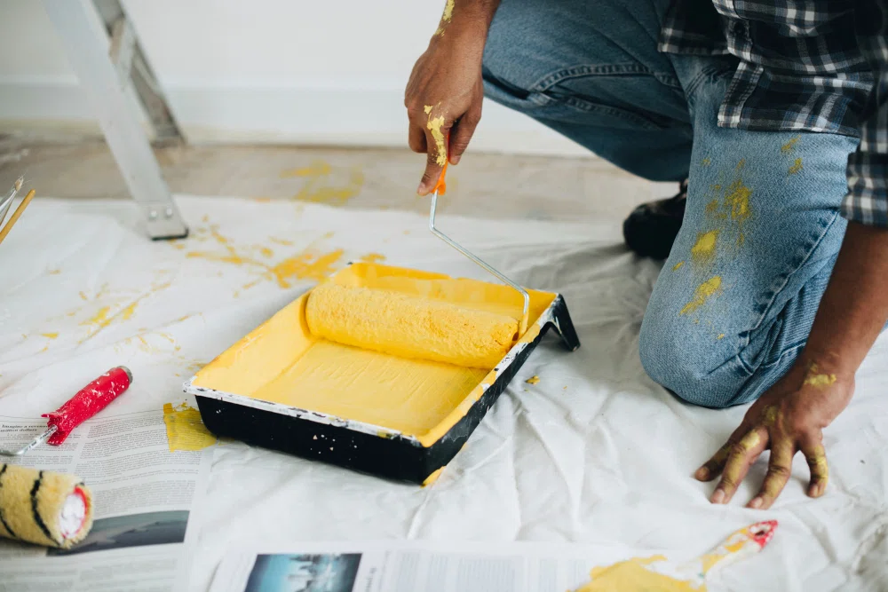 Painter preparing interior walls with a brush and roller